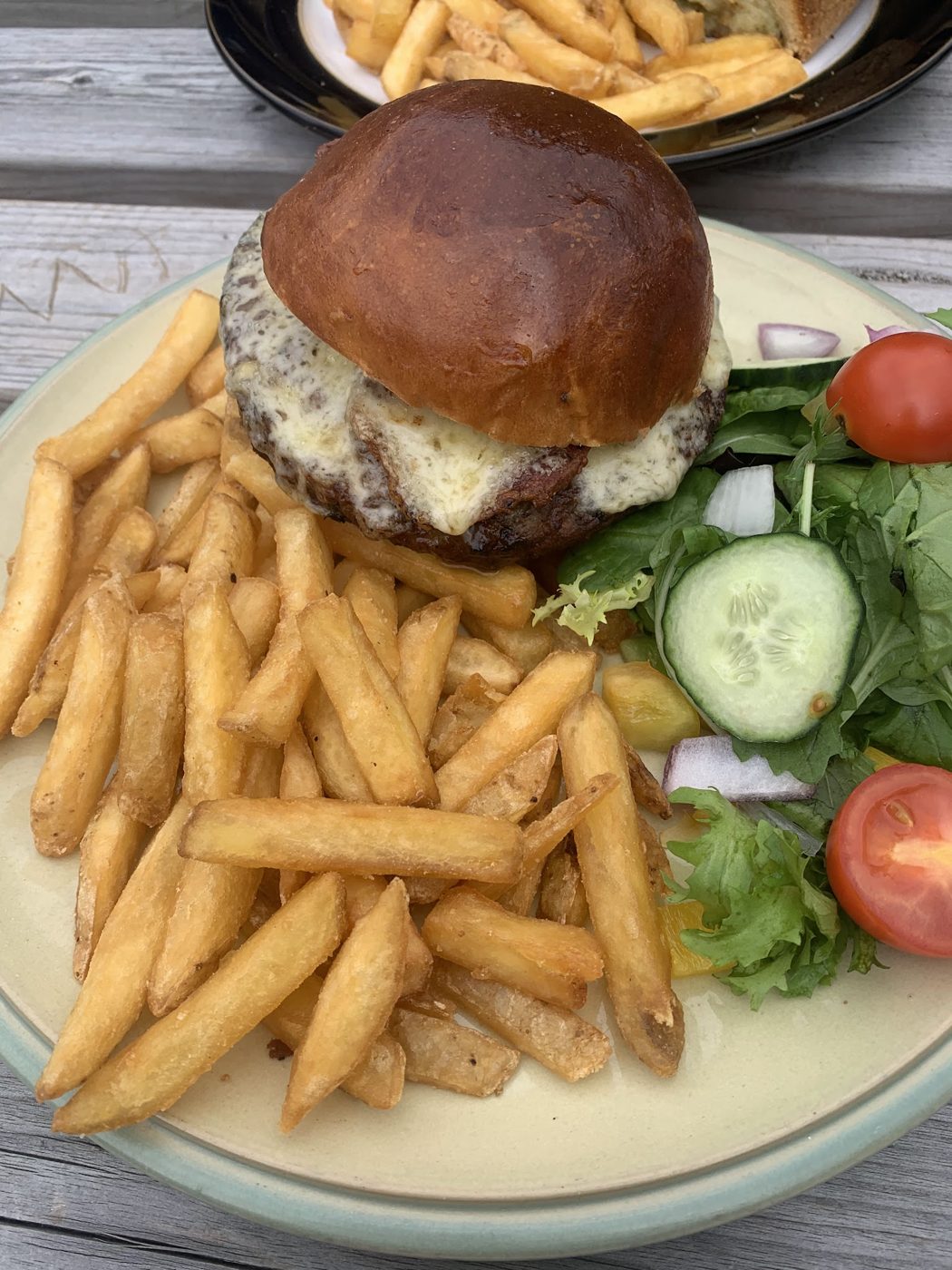 A burger with fries and salad