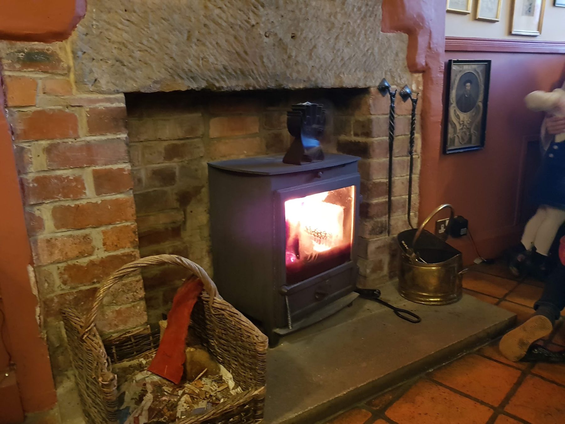 A lit log burner in a brick fireplace