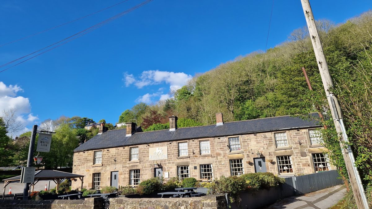 A row of stone buildings on Starkholmes Road under a blue sky